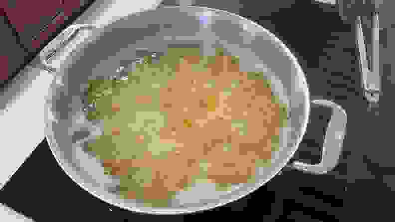 Pasta shells boiling in water inside of stainless steel pot.