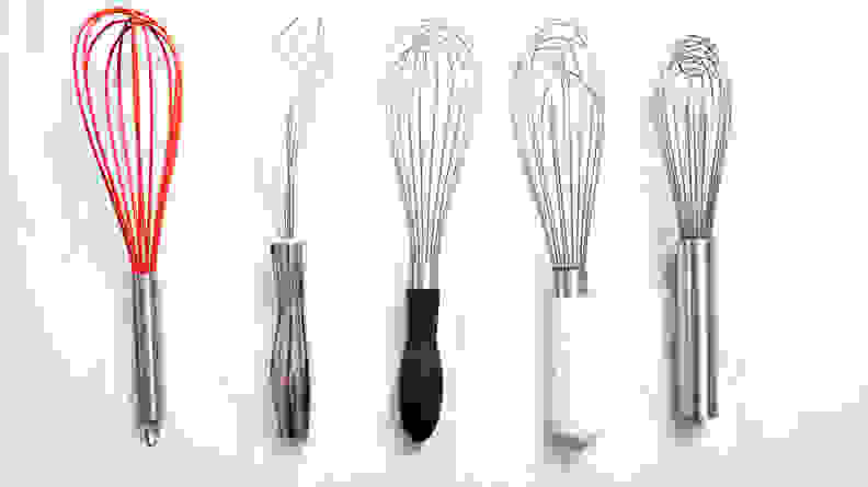 An assortment of whisks arranged on a marble countertop.