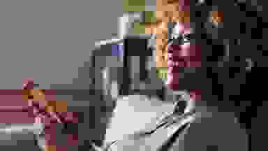 Happy woman sitting with phone in hand using the Babbel app