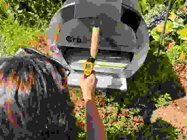 A person taking the surface temperature of the Cru 32 Pizza oven.
