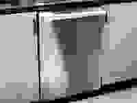 A close-up shot of a stainless steel dishwasher installed into a kitchen cabinet.