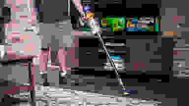 A person uses a Dyson V15 vacuum to clean the fllor