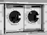 A compact washer and dryer underneath a countertop, in a cutout in the surrounding cabinetry.