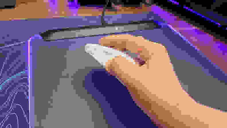 A hand gripping the Turtle Beach Burst II Air mouse on top of a purple and blue patterned mousepad.