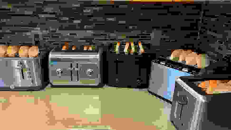 Five 4-slice toasters filled with bread slices on a countertop