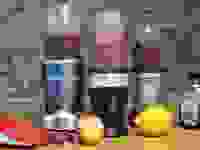 Three personal blenders with purple smoothies against a brick wall