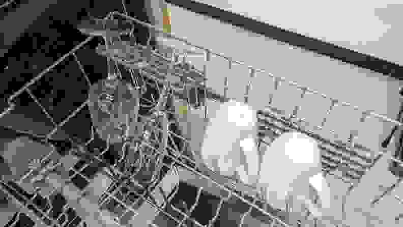 A close-up of the dishwasher's middle rack. It's holding a few coffee mugs and some stemmed glasses, which are secured by the stemware holsters.