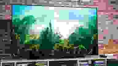 The 65-inch LG CX OLED TV displaying 4K content in front of a brick wall