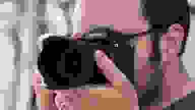 A photographer holds a camera viewfinder up to their eye to compose a shot.