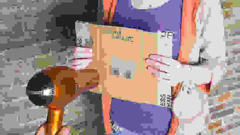 A person holding a piece of cardboard with heat sensors on it and a hair dryer pointing at the heat sensors.