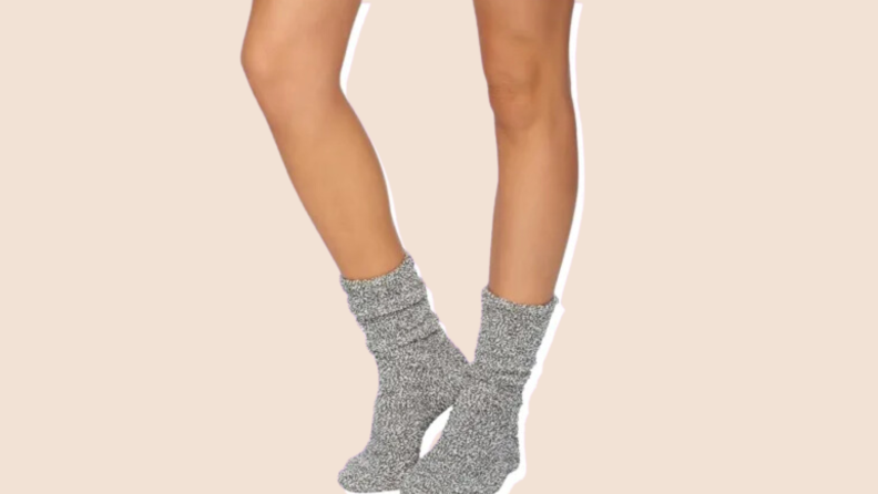 A person models a pair of  gray Barefoot Dreams Cozy Chic socks on their feet.