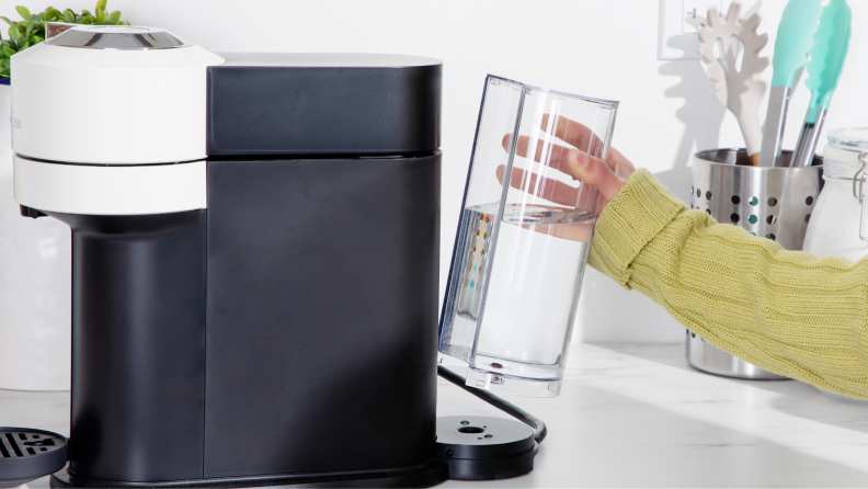 Person placing water reservoir chamber back into place on the back of the Nespresso Vertuo Next coffee maker.