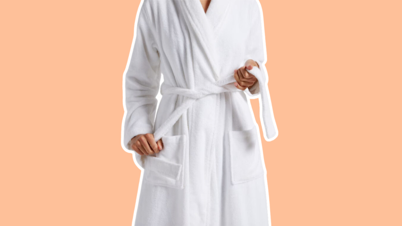 A person models a white Classic Turkish Cotton Robe by Parachute while pulling on the waist belt.