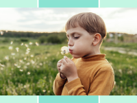 Boy blowing on dandelion while outside.