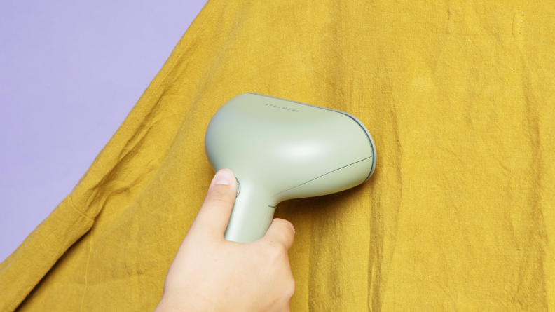 A person steaming a green linen shirt